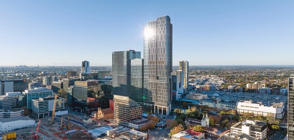 The towers of Parramatta Square extending high into the sky on a clear day as the sun reflects off their glass façades.